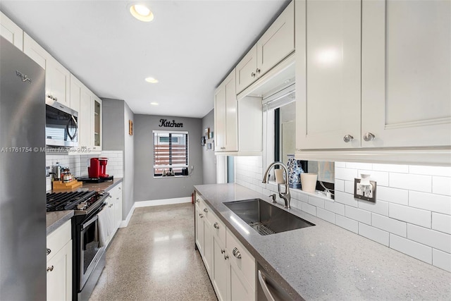kitchen with baseboards, white cabinets, a sink, appliances with stainless steel finishes, and backsplash