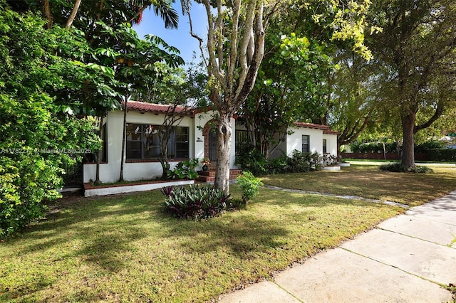 mediterranean / spanish-style home featuring a front yard, a tile roof, and stucco siding