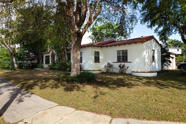 view of front of house featuring a front yard, a tiled roof, and stucco siding