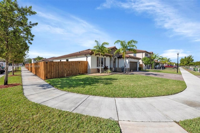 view of front facade with a front lawn, fence, stucco siding, a garage, and driveway