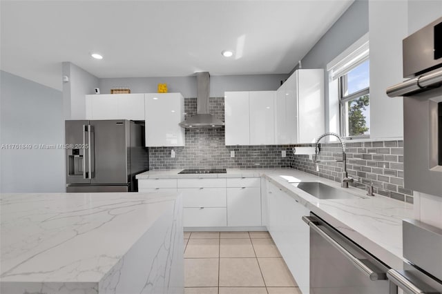 kitchen with appliances with stainless steel finishes, modern cabinets, wall chimney exhaust hood, and a sink