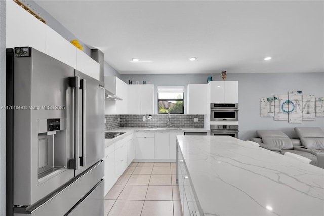 kitchen featuring tasteful backsplash, light tile patterned floors, stainless steel appliances, modern cabinets, and a sink