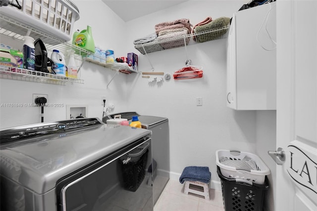 clothes washing area featuring tile patterned flooring, cabinet space, baseboards, and separate washer and dryer