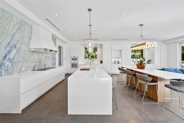 kitchen featuring black electric stovetop, a large island with sink, custom exhaust hood, white cabinetry, and modern cabinets