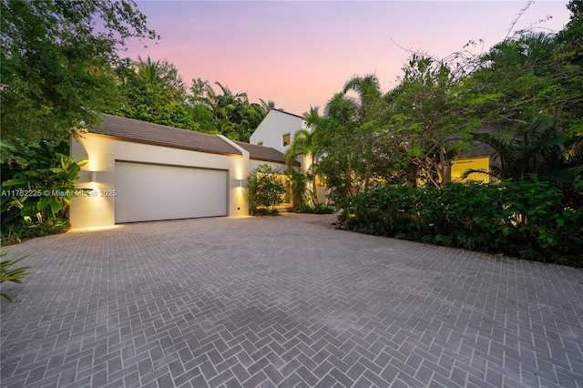 garage at dusk featuring decorative driveway