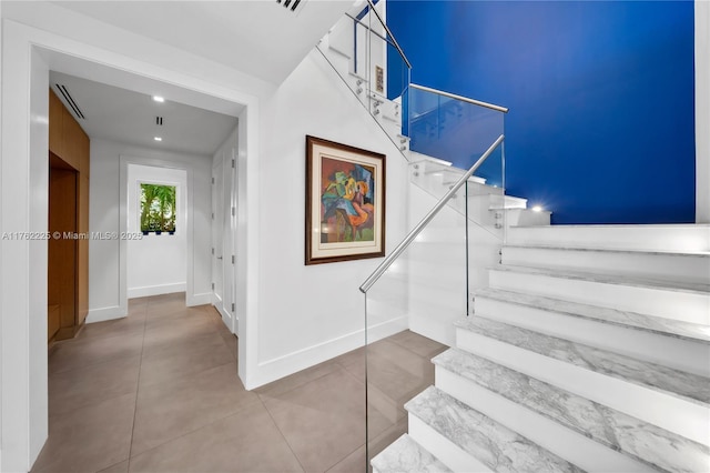 staircase featuring tile patterned floors and baseboards