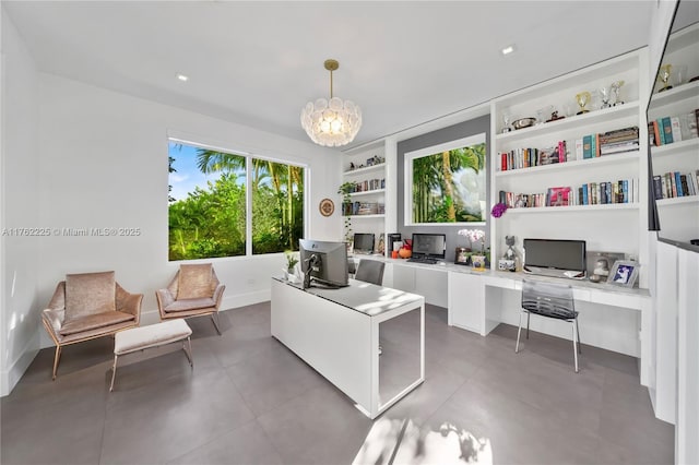 office area featuring finished concrete floors, built in shelves, baseboards, and an inviting chandelier