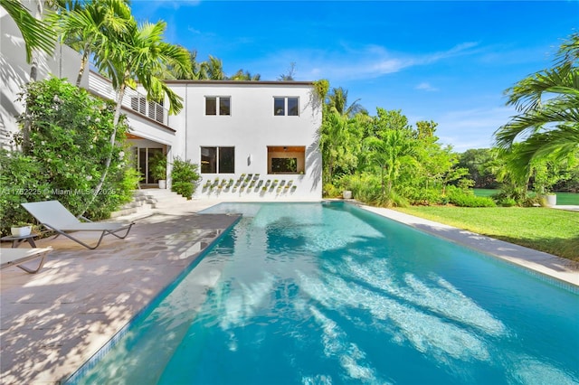 back of house featuring stucco siding, a patio, a yard, an outdoor pool, and a balcony