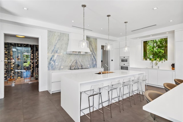 kitchen with modern cabinets, an island with sink, black electric cooktop, and a sink