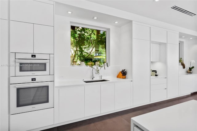 kitchen with a sink, visible vents, modern cabinets, and light countertops