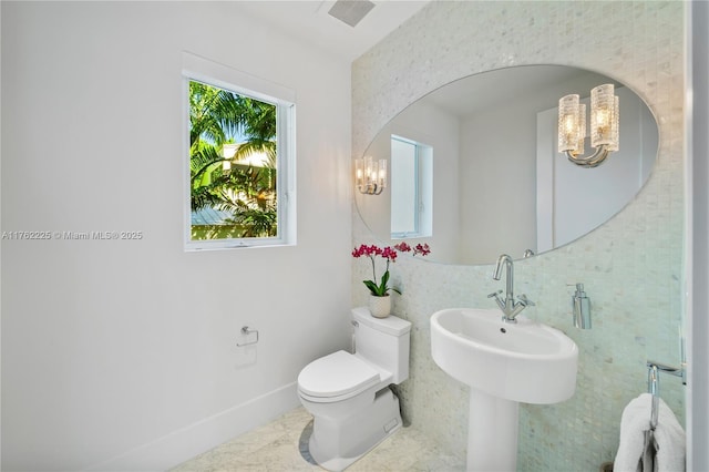 half bathroom with visible vents, baseboards, toilet, and an inviting chandelier