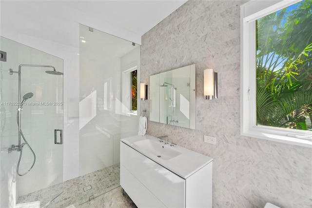 bathroom with plenty of natural light, a stall shower, tile walls, and vanity