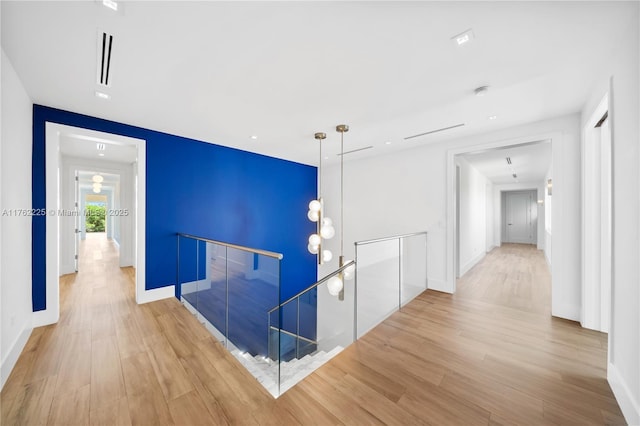 hallway with baseboards, an upstairs landing, and wood finished floors