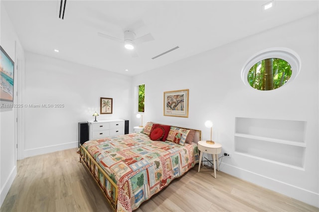 bedroom featuring visible vents, a ceiling fan, baseboards, and wood finished floors