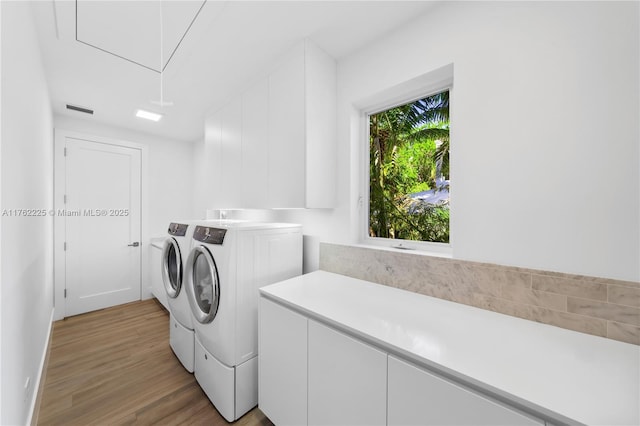 clothes washing area featuring attic access, light wood-style flooring, visible vents, and washer and clothes dryer