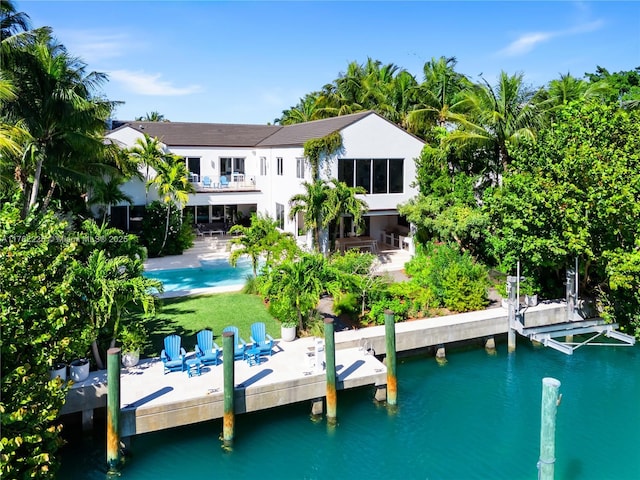 view of dock with a balcony, a patio area, an outdoor pool, and a water view