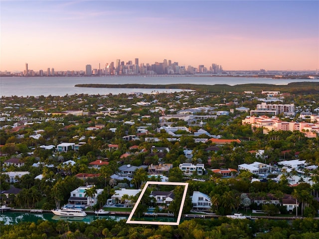 aerial view at dusk featuring a view of city and a water view