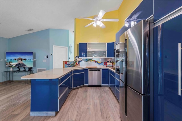 kitchen featuring visible vents, blue cabinetry, light wood-type flooring, appliances with stainless steel finishes, and a peninsula