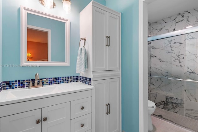 full bath with vanity, toilet, and a marble finish shower