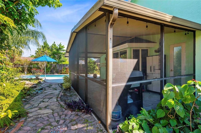 view of side of home featuring a fenced in pool, fence, and a sunroom