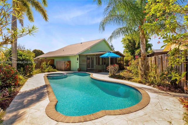 outdoor pool with a patio area, a jacuzzi, a fenced backyard, and a sunroom