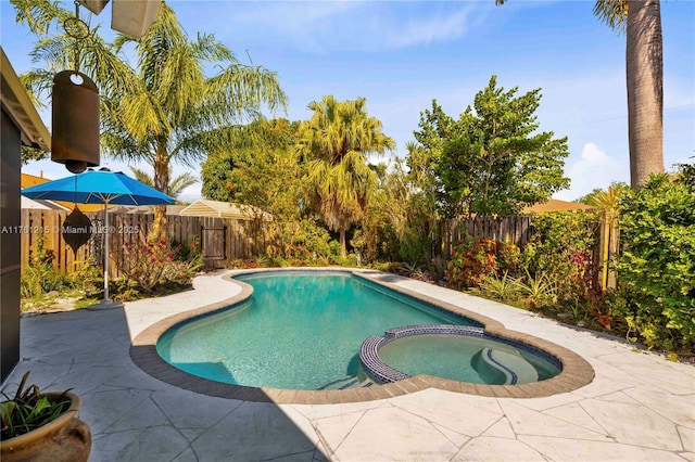 view of pool featuring a patio area, a pool with connected hot tub, and a fenced backyard