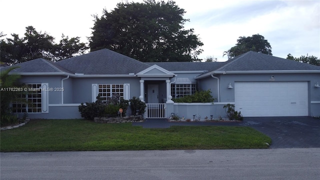 ranch-style house featuring aphalt driveway, a front yard, an attached garage, and stucco siding