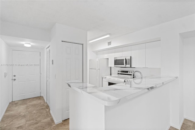 kitchen with electric range, visible vents, stainless steel microwave, freestanding refrigerator, and white cabinets