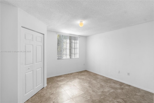 empty room with a textured ceiling and baseboards