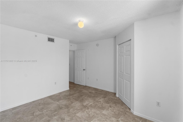 unfurnished bedroom featuring visible vents, baseboards, a textured ceiling, and a closet