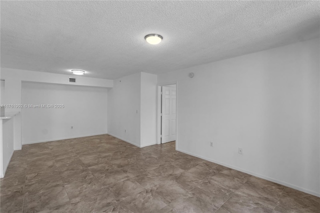 spare room with visible vents, a textured ceiling, and baseboards