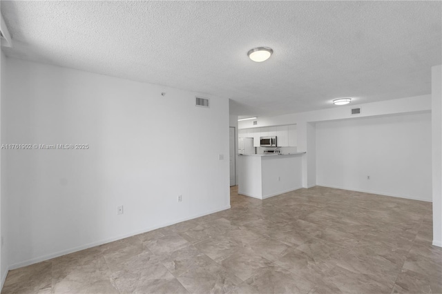 unfurnished living room with visible vents, baseboards, and a textured ceiling