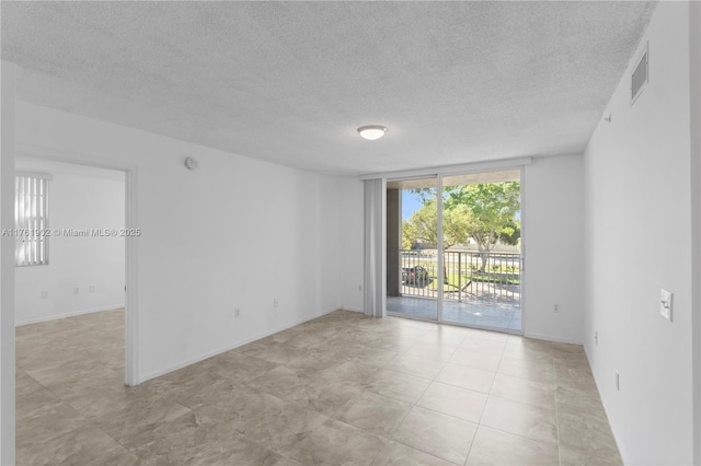 unfurnished room featuring visible vents, baseboards, a textured ceiling, and floor to ceiling windows