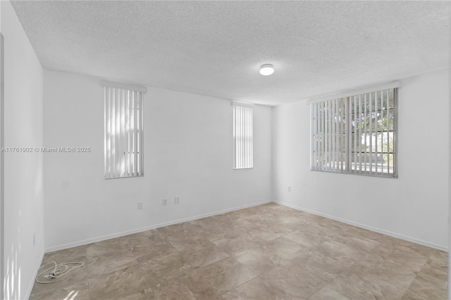 empty room featuring a healthy amount of sunlight, baseboards, and a textured ceiling