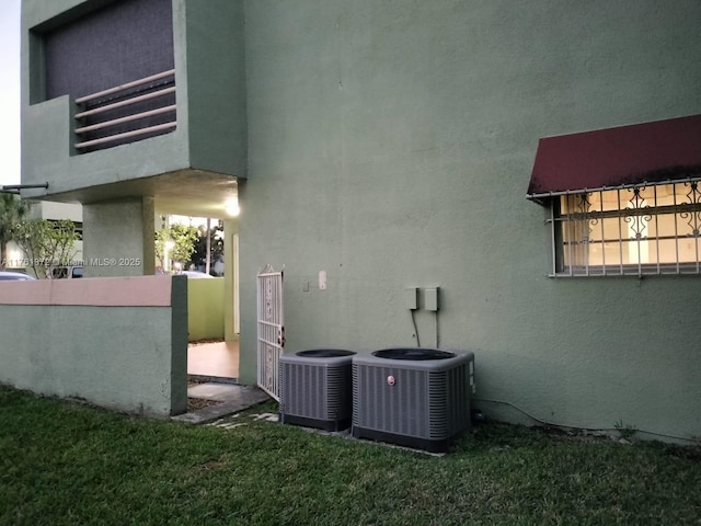 view of home's exterior with a yard, central AC, and stucco siding