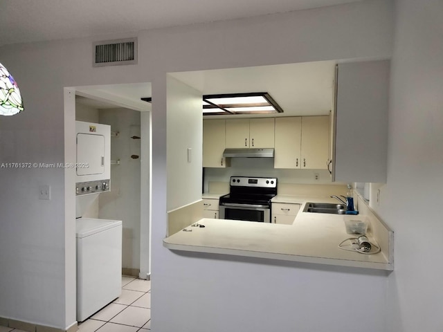 kitchen with visible vents, stacked washer and clothes dryer, under cabinet range hood, a sink, and stainless steel electric stove