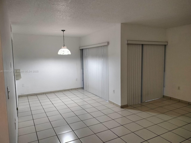 spare room with baseboards, a textured ceiling, and light tile patterned flooring