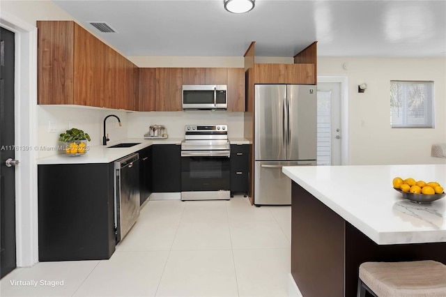 kitchen with visible vents, light countertops, appliances with stainless steel finishes, brown cabinetry, and a sink