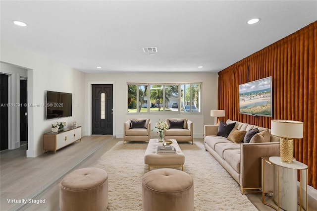 living area featuring recessed lighting, visible vents, and wood walls