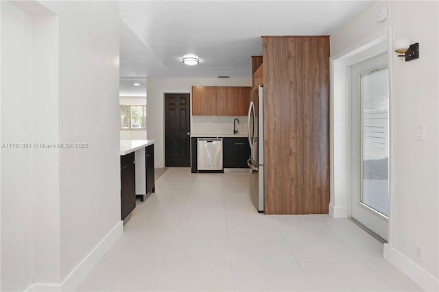 kitchen featuring brown cabinetry, a sink, stainless steel appliances, light countertops, and modern cabinets