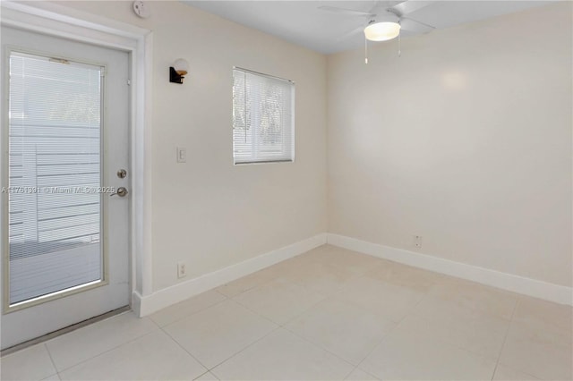 empty room featuring light tile patterned floors, a ceiling fan, and baseboards