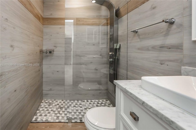 bathroom featuring vanity, toilet, and a tile shower