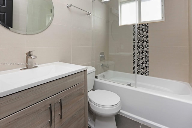 bathroom featuring vanity, tile walls, toilet, and washtub / shower combination