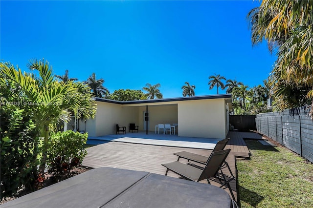 back of house with stucco siding, fence private yard, and a wooden deck