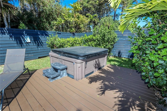 wooden terrace with a garage, a hot tub, and a fenced backyard