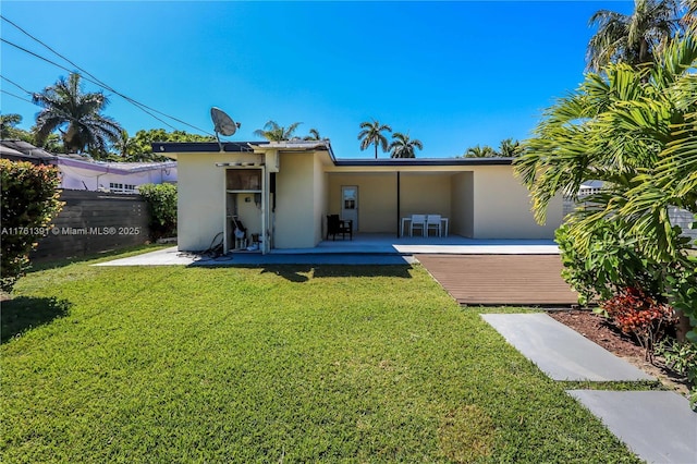 rear view of house with a patio area, fence, a lawn, and stucco siding