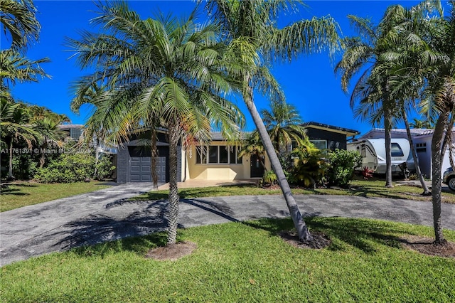 view of front of property featuring stucco siding, a front yard, an attached garage, and driveway