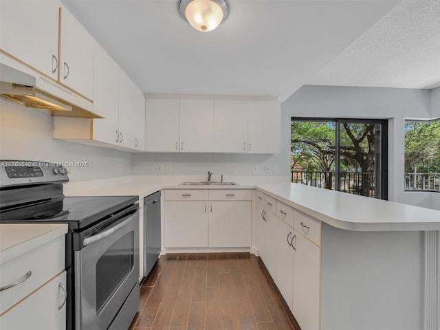 kitchen with stainless steel appliances, a peninsula, dark wood finished floors, and light countertops