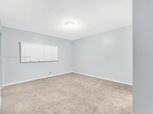 carpeted empty room featuring baseboards and a textured ceiling