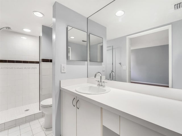 bathroom featuring tile patterned flooring, visible vents, toilet, a tile shower, and vanity